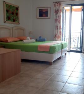 1 dormitorio con 1 cama con sábanas verdes y rosas en Studios Edem, en Agios Ioannis Kaspaka