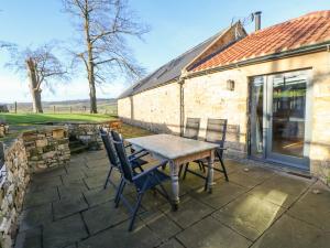 una mesa y sillas en un patio fuera de un edificio en The Byre, Sedbury Park Farm, en Richmond