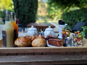 una bandeja de comida con pan y carne y botellas de zumo en Chambre d'hôtes SOPHORA - Les Clés des Lys, en Moret-sur-Loing