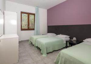 a hotel room with two beds and a window at Santamaria Village Resort Ascea in Ascea