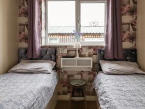 sypialnia z 2 łóżkami i oknem z fioletowymi zasłonami w obiekcie The Old Hen Shed w mieście Ingrow