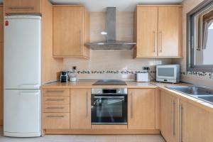 a kitchen with wooden cabinets and a white refrigerator at 797 HOLIDAY RENTALS - BELLAGIO- Elegante piso para 6 a 1 min de la playa, con piscina interior y exterior, SPA con jacuzzi in Benalmádena