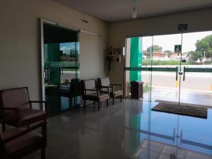 a waiting room with chairs and a large glass door at Hotel Samambaia in Indiara 