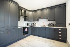 uma cozinha com armários azul marinho e pisos brancos em Mabel's Maison by Escape Ordinary em Enniskillen