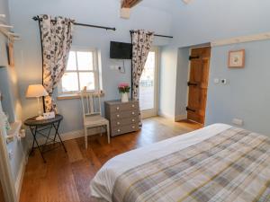a bedroom with a bed and a dresser and a television at The Cartshed, Sedbury Park Farm in Gilling