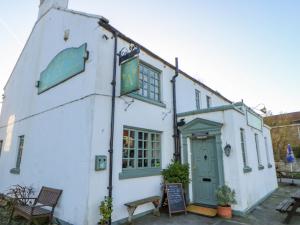 a white building with a green door at The Cartshed, Sedbury Park Farm in Gilling