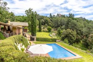 a house with a swimming pool and an umbrella at Catalunya Casas Stunning Costa Brava mountain retreat and 30kms away from the beach in Sant Feliu de Buixalleu