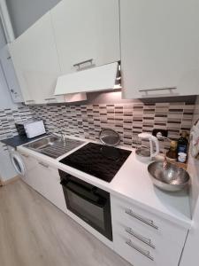 una cucina bianca con piano cottura e lavandino di Apartments via Roma a Rovereto