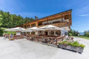a building with tables and umbrellas in front of it at Gasthof-Ferienwohnungen Dürrlehen in Berchtesgaden