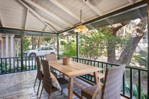 einen Holztisch und Stühle auf einer Terrasse mit einem Baum in der Unterkunft Palmetto Cottage - 116 Florence Street in King City