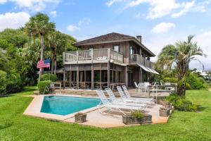 a house with a swimming pool and two lawn chairs at This is It - 4314 Sixteenth Street in Saint Simons Island