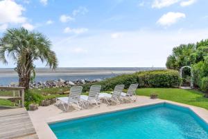 a pool with chairs and a table and the beach at This is It - 4314 Sixteenth Street in Saint Simons Island
