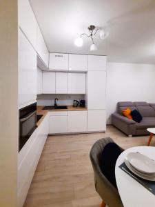 a kitchen with white cabinets and a table and a couch at Primavera - Apartament nad rzeką - parking w cenie in Wrocław