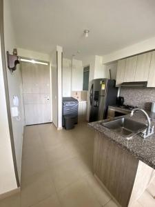 a kitchen with a sink and a refrigerator at Ven a recargar energías. in Girardot