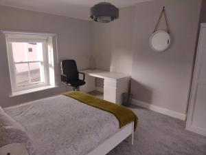 a bedroom with a bed and a desk and a chair at Ryan's Cottage in Rostrevor