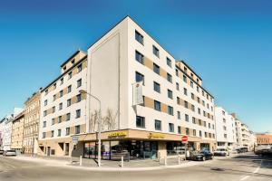 duży biały budynek przy ulicy miejskiej z światłem ulicznym w obiekcie B&B Hotel Wien-Stadthalle w Wiedniu