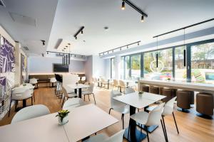 a restaurant with white tables and chairs and windows at B&B Hotel Wien-Stadthalle in Vienna