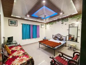 a bedroom with a bed and a couch and a window at Krishna Niwas in Mahabaleshwar