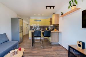 a kitchen and living room with yellow cabinets and a blue couch at Apartment Niksa in Pula