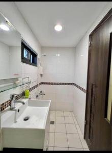Baño blanco con lavabo y espejo en Humble Room, en Hualien City
