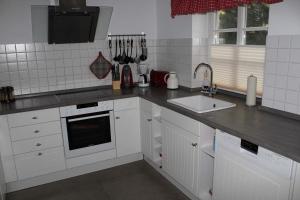uma cozinha branca com um lavatório e uma bancada em Koni-s-Hus-2 em Ording