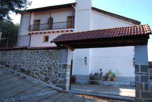 a white house with a stone wall and a gate at Hotel Cinco Castaños in Candelario