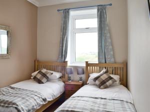 two beds in a room with a window at Bankswood Cottage in Ruthwell