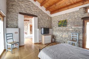 1 dormitorio con pared de piedra, 1 cama y 2 sillas en Romantic Boutique Hospitality en Revine Lago