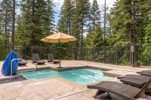 a swimming pool with an umbrella and chairs at Escape to Ptarmigan Village 91 in Whitefish