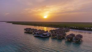 an aerial view of a resort on the water at sunset at Palafitos Overwater Bungalows El Dorado Maroma - Adults Only in Playa del Carmen