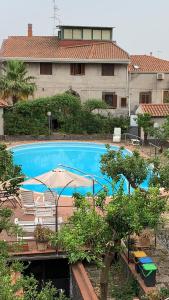 a large blue swimming pool with an umbrella and chairs at Villa con piscina in Mascalucia