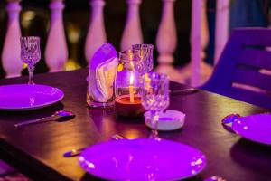 una mesa con platos púrpura y gafas. en Baga Beach Myron, en Baga