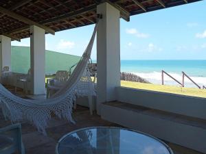 a porch with a hammock and a view of the beach at Casa dos Ximenes - Beira Mar da Taíba - Ótima localização in Taíba