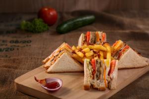 a sandwich and french fries on a cutting board at Baga Beach Myron in Baga