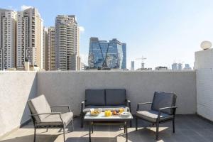 a balcony with two chairs and a table with fruit on it at Pleasent Day by HolyGuest in Tel Aviv