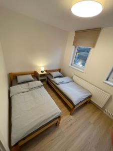 2 camas en una habitación pequeña con ventana en APARTAMENTY GUZIK 22 en Krosno