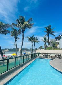 - une piscine à côté d'une plage bordée de palmiers dans l'établissement KING's FLAT HOTEL NATAL, à Natal