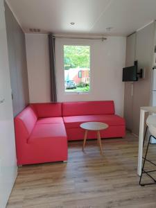 un soggiorno con divano rosso e tavolo di Mobile Home tout confort C13 Domaine de Lanniron a Quimper