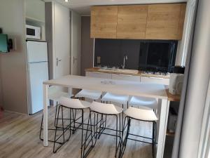 uma cozinha com uma mesa branca e bancos de bar em Mobile Home tout confort C13 Domaine de Lanniron em Quimper