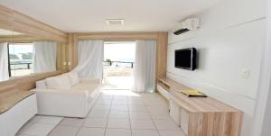 a living room with a couch and a tv on a wall at KING's FLAT HOTEL NATAL in Natal