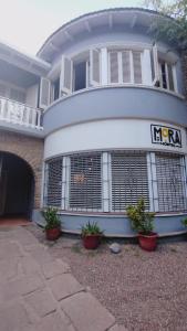 une grande maison blanche avec des plantes en pot devant elle dans l'établissement Mora Hostel, à Mendoza