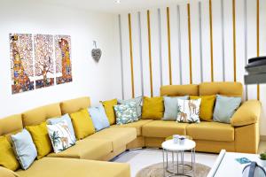 a living room with a yellow couch with colorful pillows at Fleming Apartment in Tavira