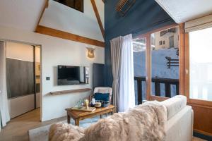 a living room with a couch and a large window at Le Chalerick - triplex rénové 6 à 8 personnes - hyper centre Valmeinier 1800 - ski aux pieds in Valmeinier