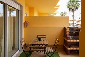 a table and chairs on a balcony with a yellow wall at Fleming Apartment in Tavira