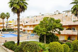 an apartment building with a swimming pool and palm trees at Fleming Apartment in Tavira