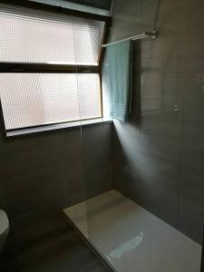 a bathroom with a glass shower with a window at Beach House in Póvoa de Varzim