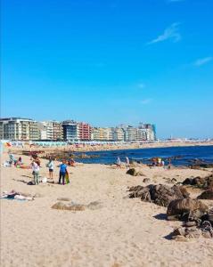 een groep mensen op een strand met de oceaan bij Beach House in Póvoa de Varzim