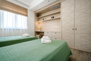 duas camas num quarto com lençóis verdes e toalhas em Lustica Apartments Marina em Tivat