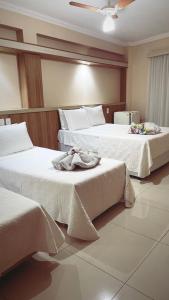 Dos camas en una habitación de hotel con toallas. en Hotel Lux, en Poços de Caldas