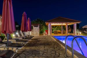 a resort pool with chairs and umbrellas at night at House vacation with pool,near Šibenik in Planjane